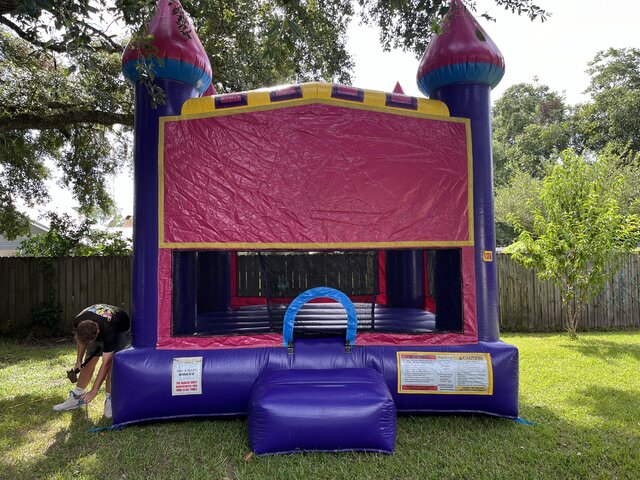 A Purple and Pink Castle Bounce House with Basketball Goal