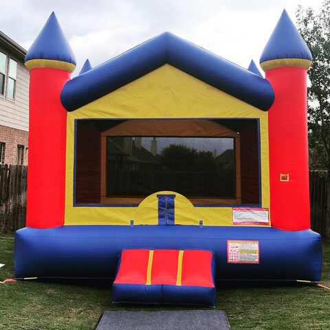 15' X 15' Red, blue, yellow v-roof castle bounce house on grass in backyard for party.