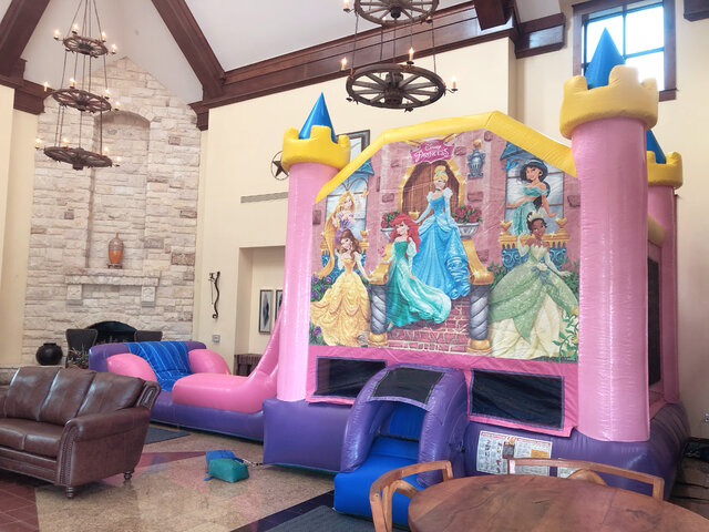 Inflatable Disney princess bounce house with slide set up inside HOA community center..