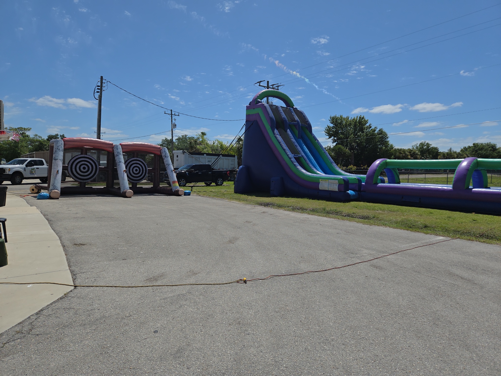 Axe throw game, water slide and obstacle course set up for a large event