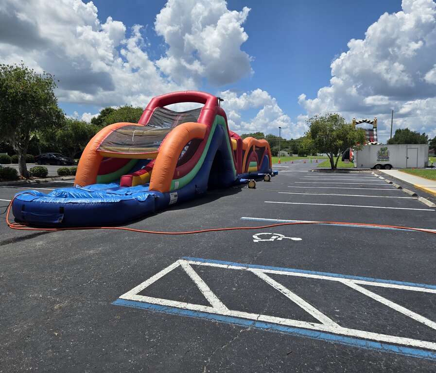 70-foot Warrior Dash obstacle course with splash pool on a church parking lot in Saint Cloud, FL, with a tall water slide in the background