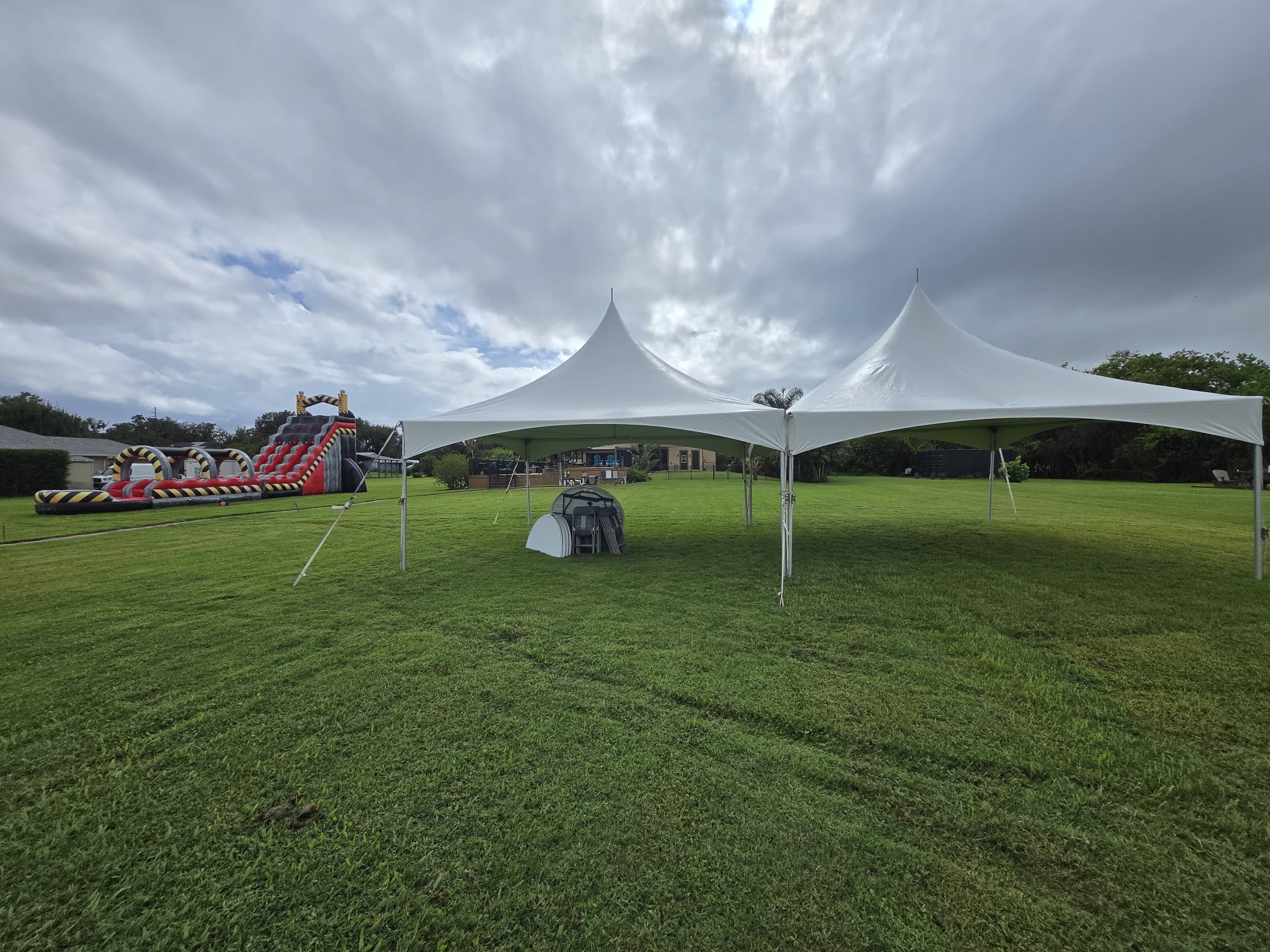 Two high-peak tents and a large water slide set up on a field for a fall event