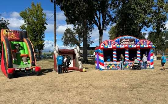 Bounce-N-Battle carnival game booths and inflatables set up at an outdoor community event