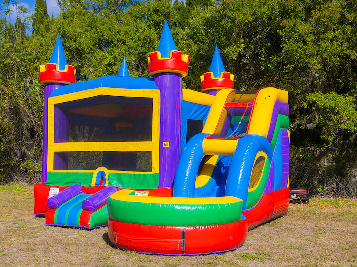 A clean castle bounce house with slide and splash pool, set up on a lawn