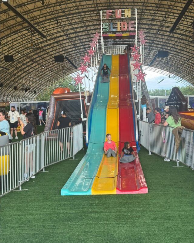 Kids racing down a three-lane carnival fun slide inside a covered dome