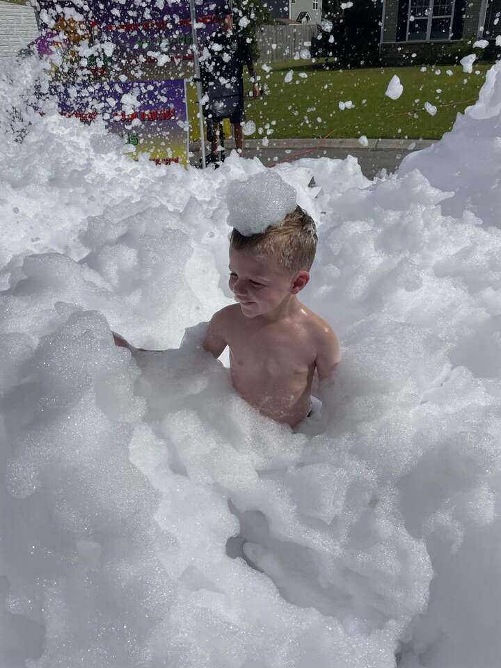 Child smiling as he is covered in foam