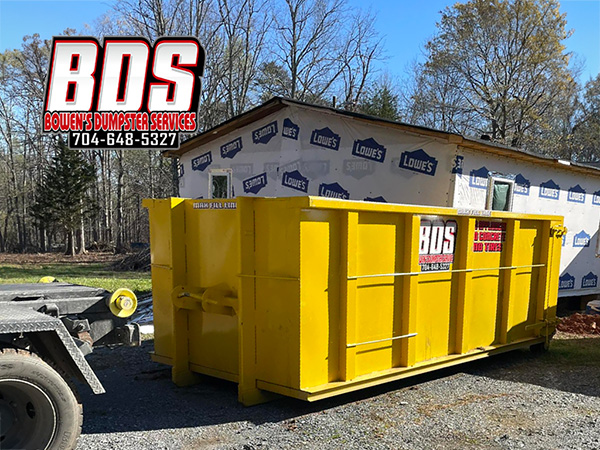 A loaded Bowen's Dumpster Services container being hauled away from a renovation site.
