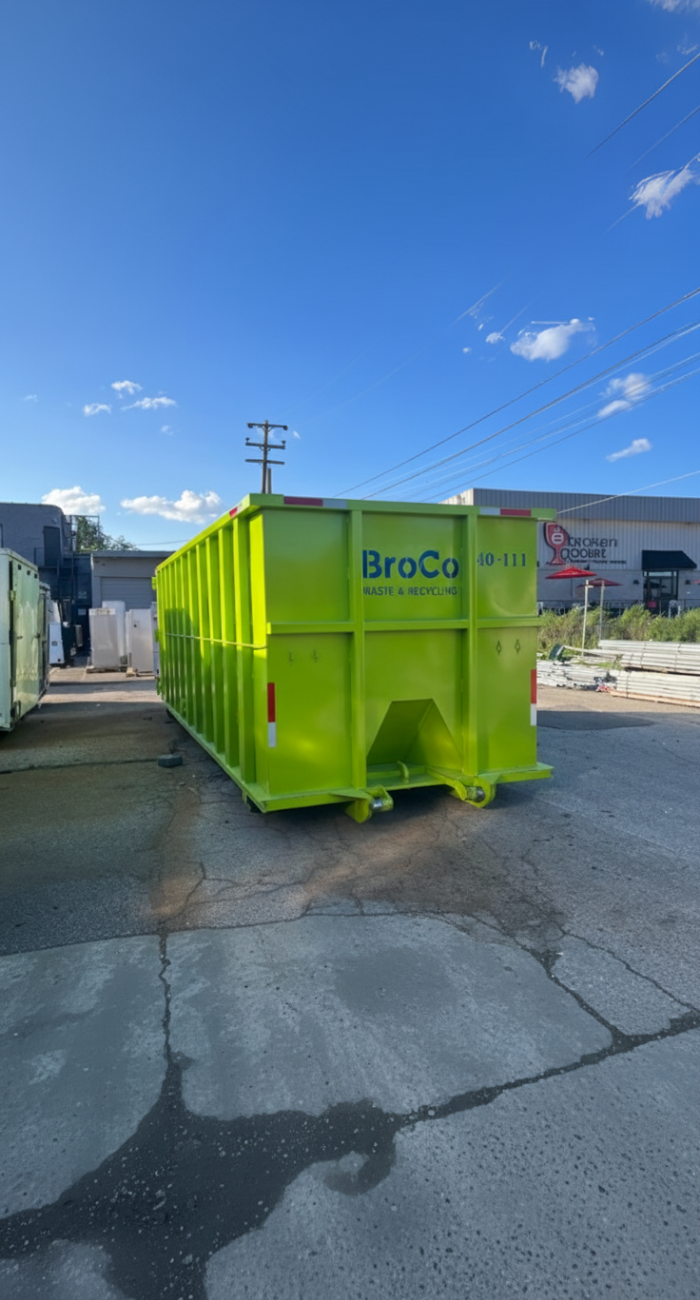Broco Waste green roll-off dumpster in a commercial yard or lot.