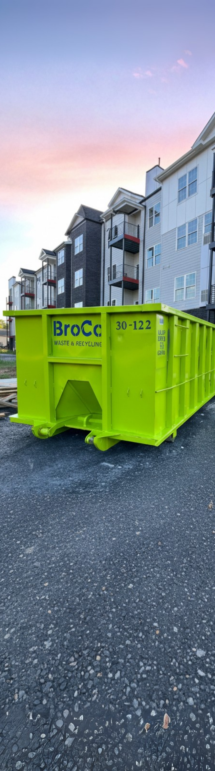 Broco Waste bright green dumpster at an apartment complex construction site.