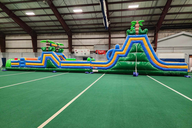 Big unicorn themed bounce house and slide that is decorated with clouds and rainbows