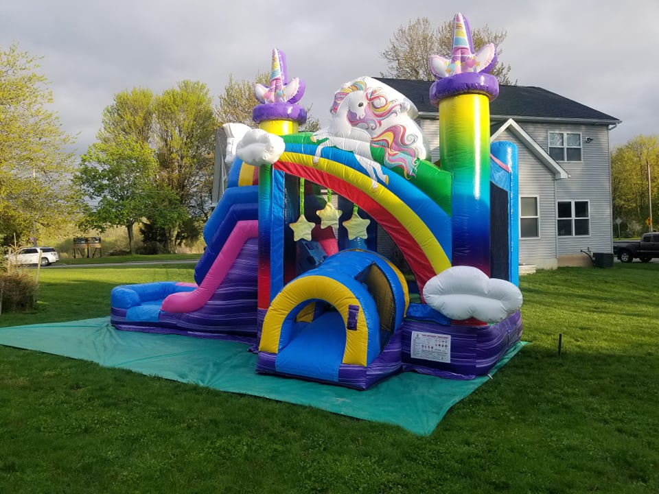 Rainbows and unicorns fill the air with this unicorn themed bounce house with slide