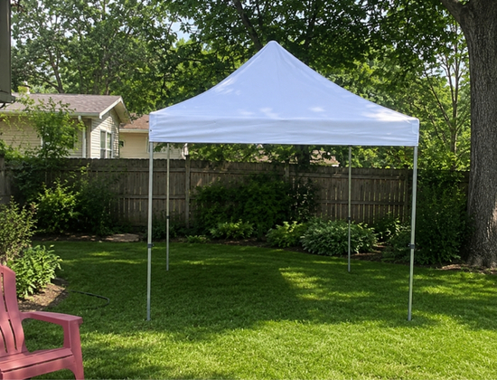 White high peak tent on a grassy backyard lawn