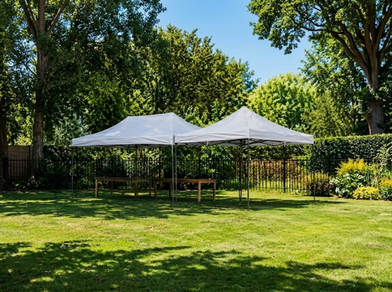 Two white canopy tents set up on a grassy lawn in a park-like setting