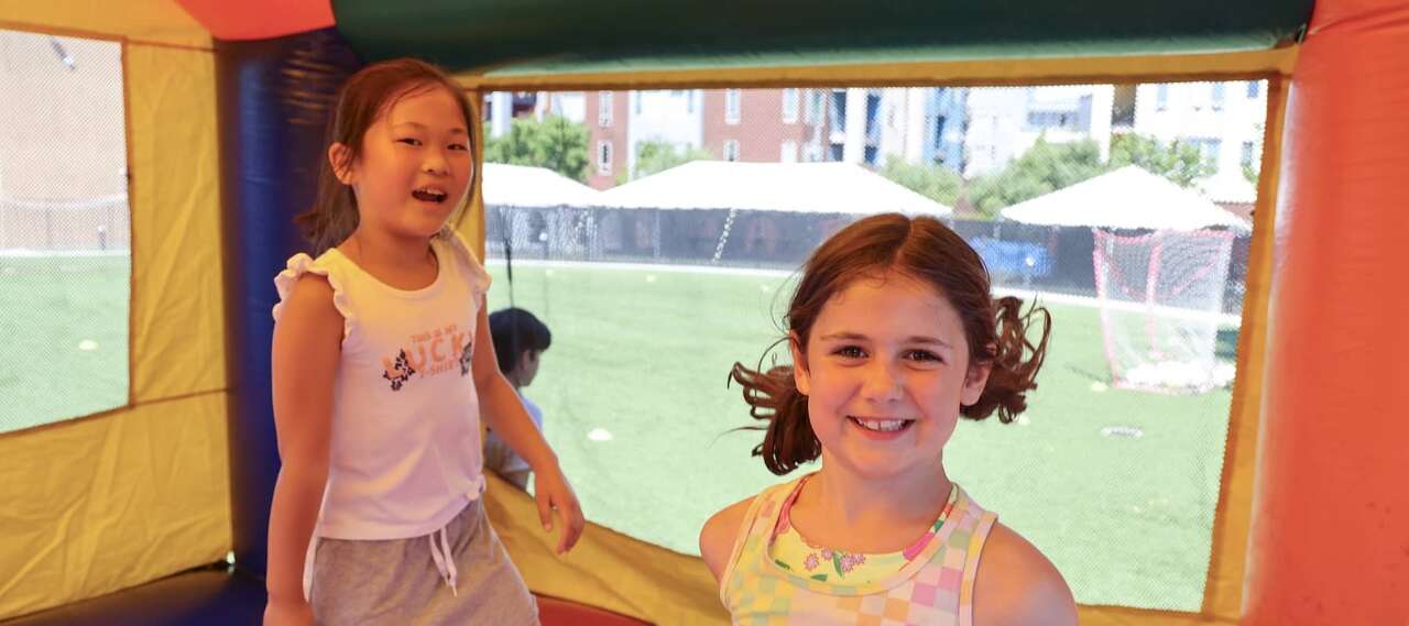 Two smiling kids playing inside a bounce house during a sunny event, showing the fun side of choosing a bounce house vs. water slide for your Boardman, OH event.
