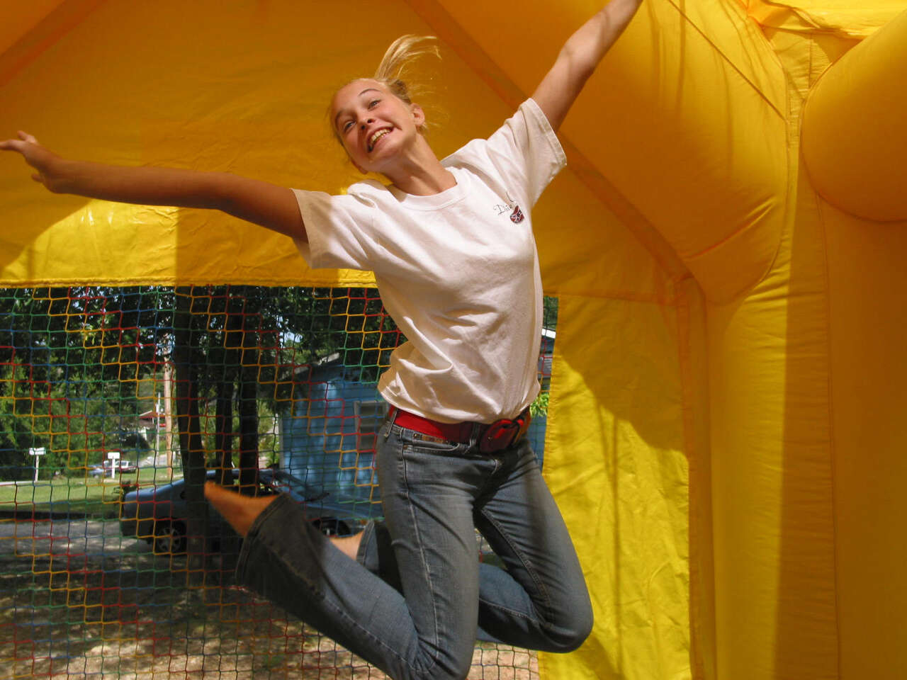 Smiling teen jumping inside a bright yellow bounce house rental in Canfield, OH