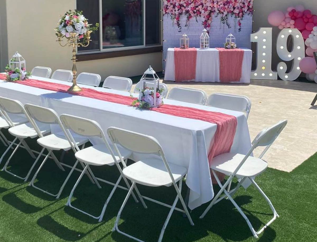 ChatGPT said:  Table and chair rentals in Canfield, OH arranged for an elegant outdoor celebration with white folding chairs, decorated banquet tables, and pink event décor