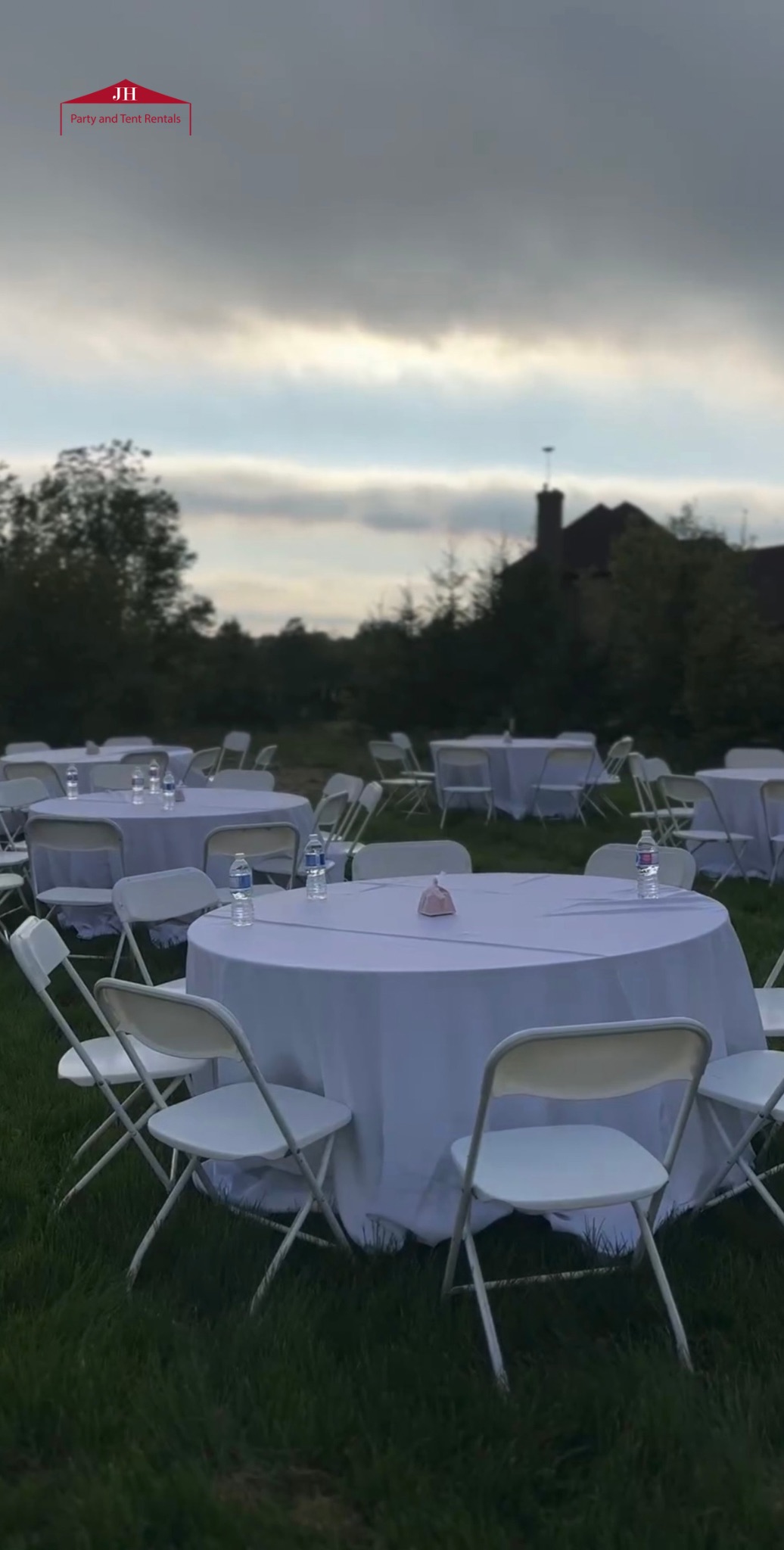 White folding chairs and round table rentals set up outdoors in Canfield, OH for an evening party or event