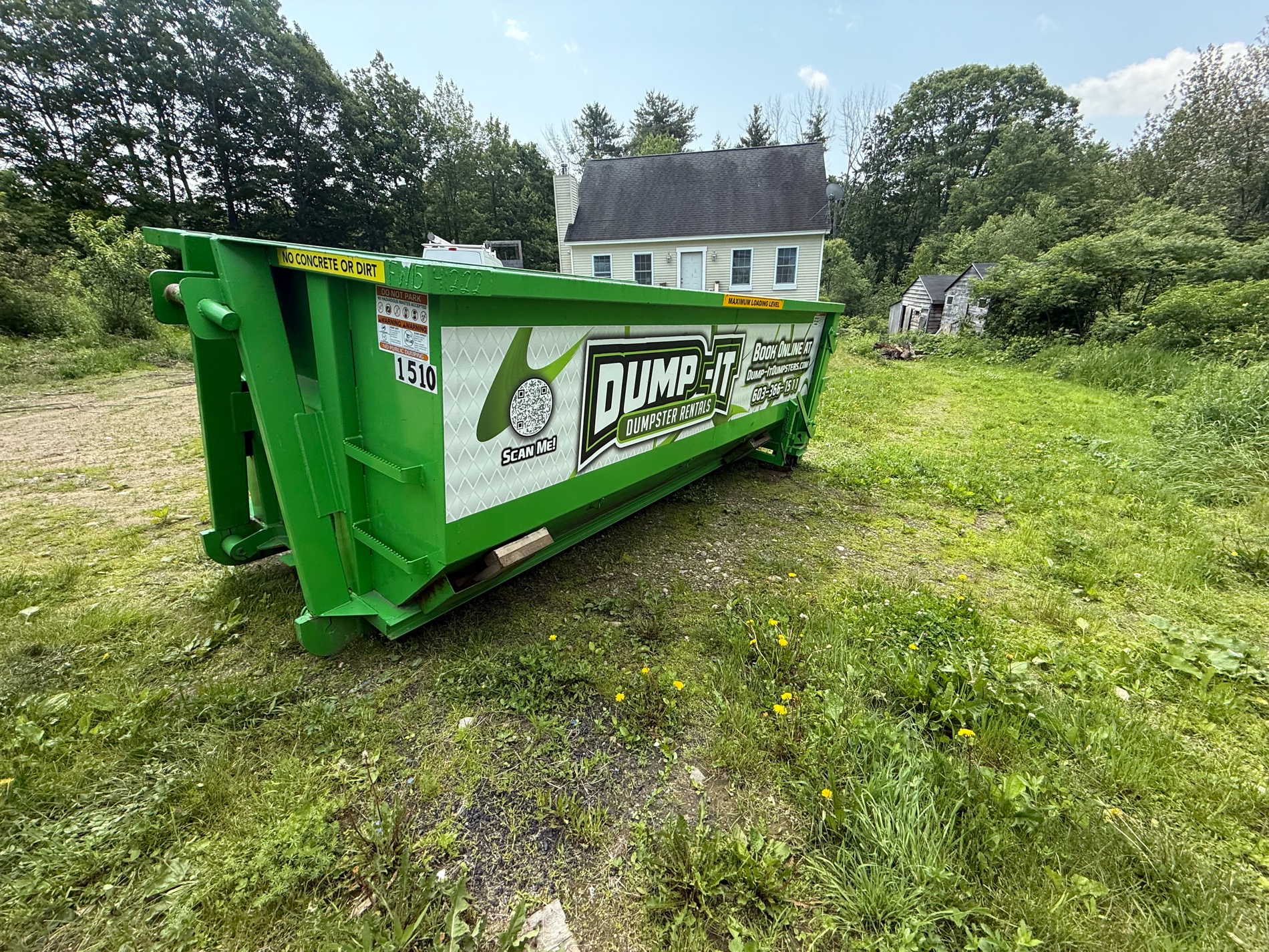 Dump-It Dumpster Rentals" logo over a driveway dumpster at night.