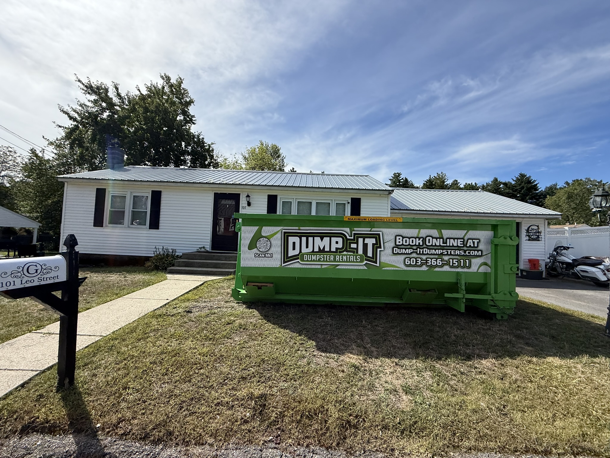 Dump-It Dumpster Rentals" logo over a driveway dumpster at night.