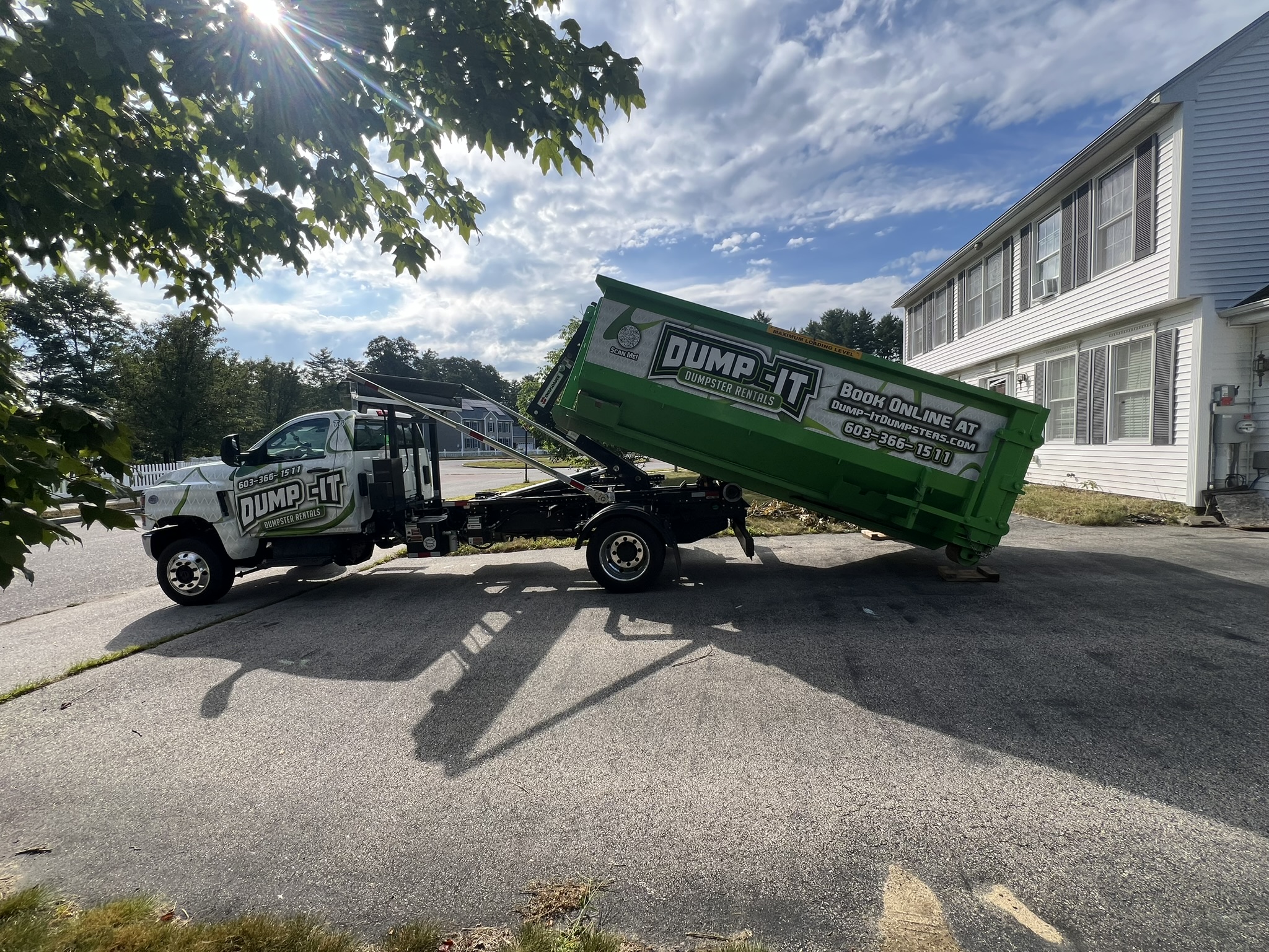 Dump-It Dumpster Rentals logo over a green dumpster in a driveway.