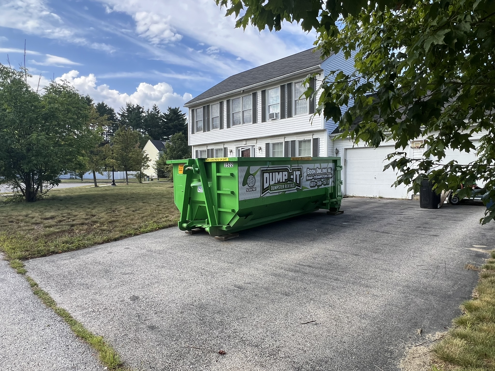 Dump-It Dumpster Rentals logo over a green dumpster in a driveway.