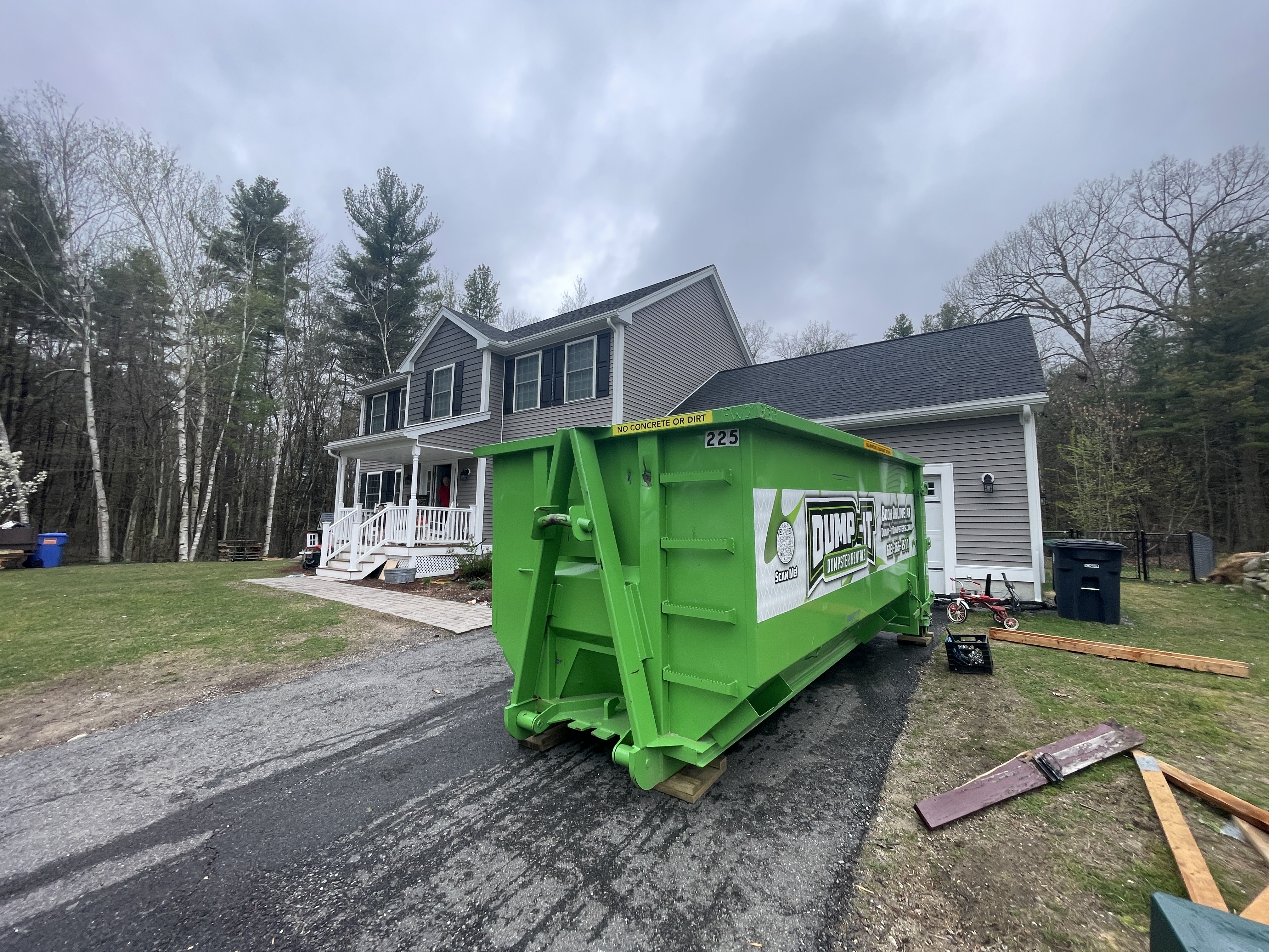 Dump-It Dumpster Rentals" logo over a green dumpster in a driveway.