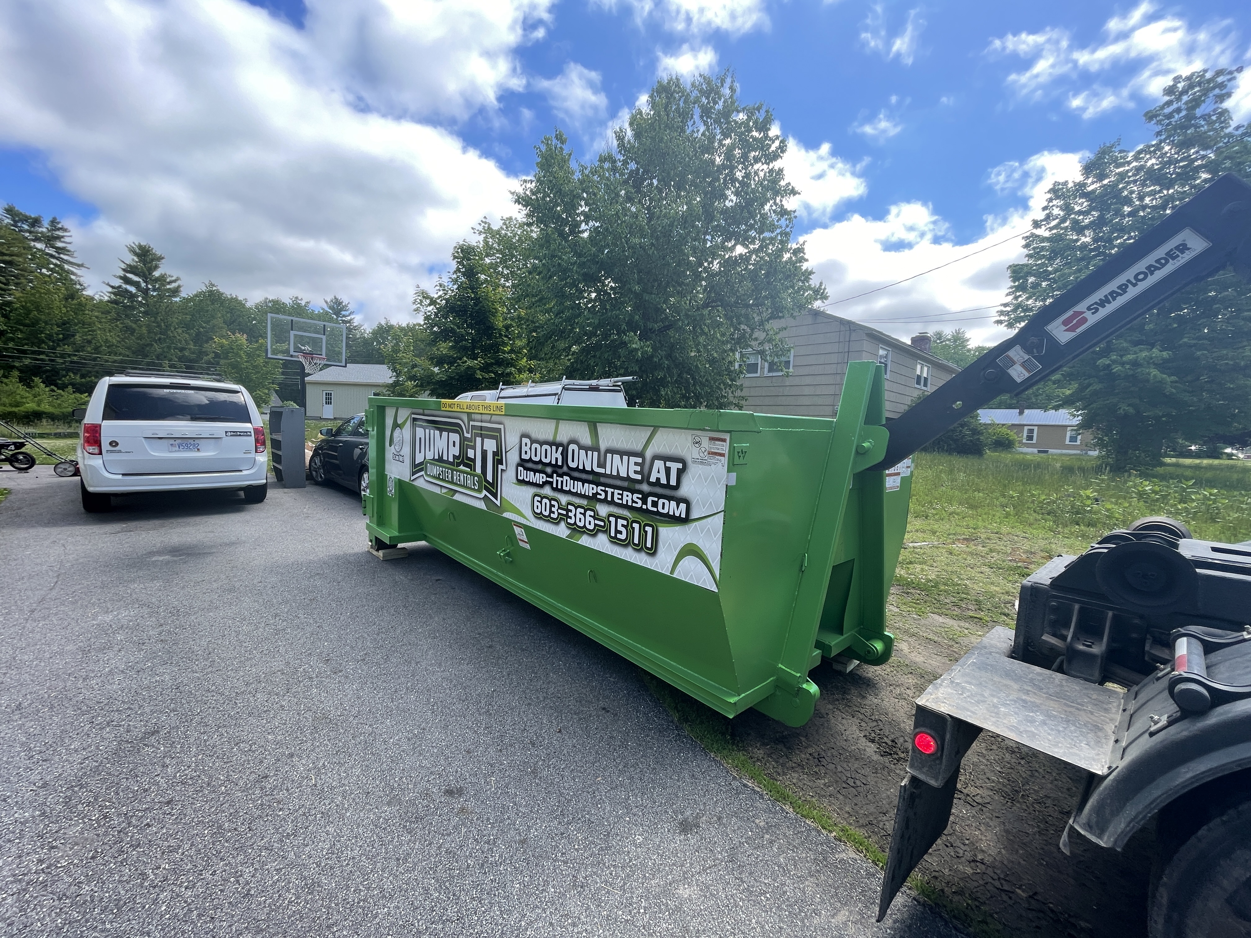 Dump-It Dumpster Rentals" logo over a driveway dumpster at night.