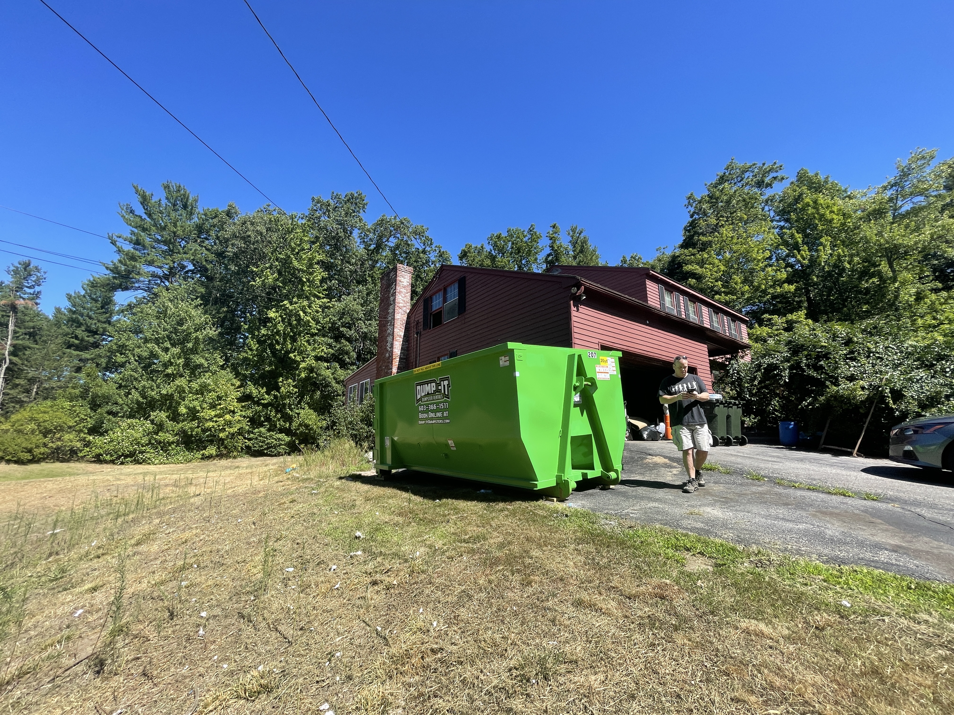 Dump-It Dumpster Rentals" logo over a green dumpster in a driveway.