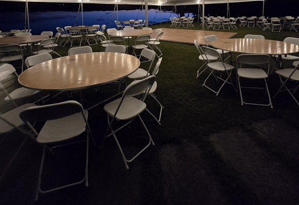 Round tables and folding chairs under event tent