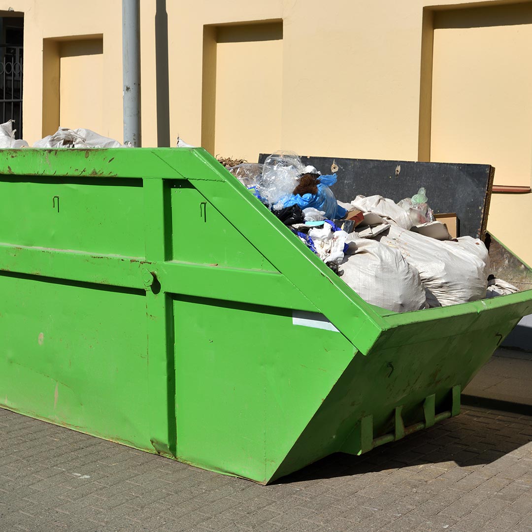 green dumpster full of trash and debri