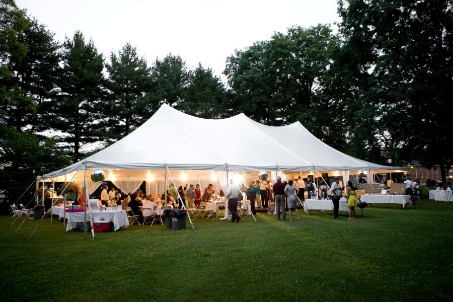 group of people gathered under a tent at sunset, having fun and enjoying themselves