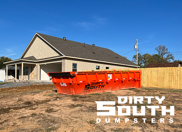 Residential construction site in Central Arkansas with a Dirty South Dumpsters roll-off dumpster placed next to a home for renovation debris removal Residential construction site in Central Arkansas with a Dirty South Dumpsters roll-off dumpster placed next to a home for renovation debris removal