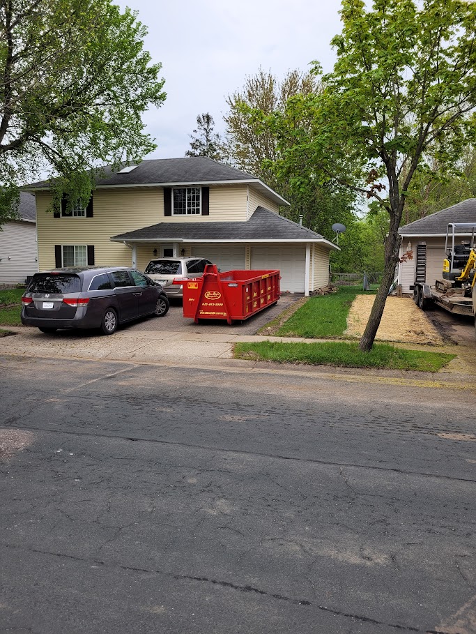 Compact red dumpster from Done Right Dumpsters in a residential driveway. Compact red dumpster from Done Right Dumpsters in a residential driveway.