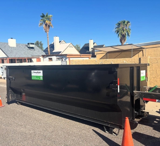 Large roll-off dumpster staged on a residential street with a safety cone by Dump Right LLC