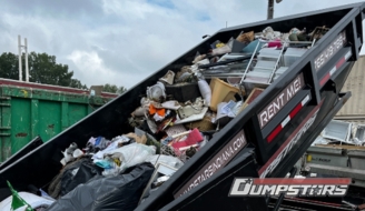 Black roll-off dumpster filled with mixed waste and debris being hauled away Black roll-off dumpster filled with mixed waste and debris being hauled away
