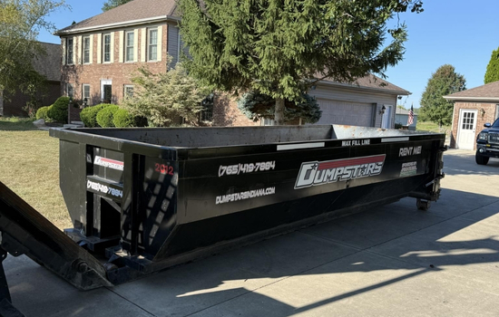Black roll-off dumpster placed in a residential driveway Black roll-off dumpster placed in a residential driveway