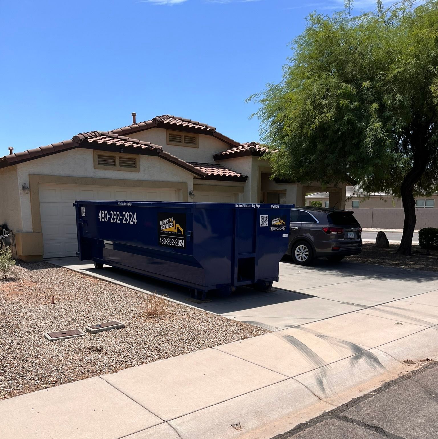  Dumpstar Services dark blue roll-off dumpster in a residential driveway.