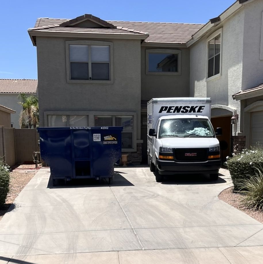  Dumpstar Services blue dumpster and a Penske moving truck in a driveway.