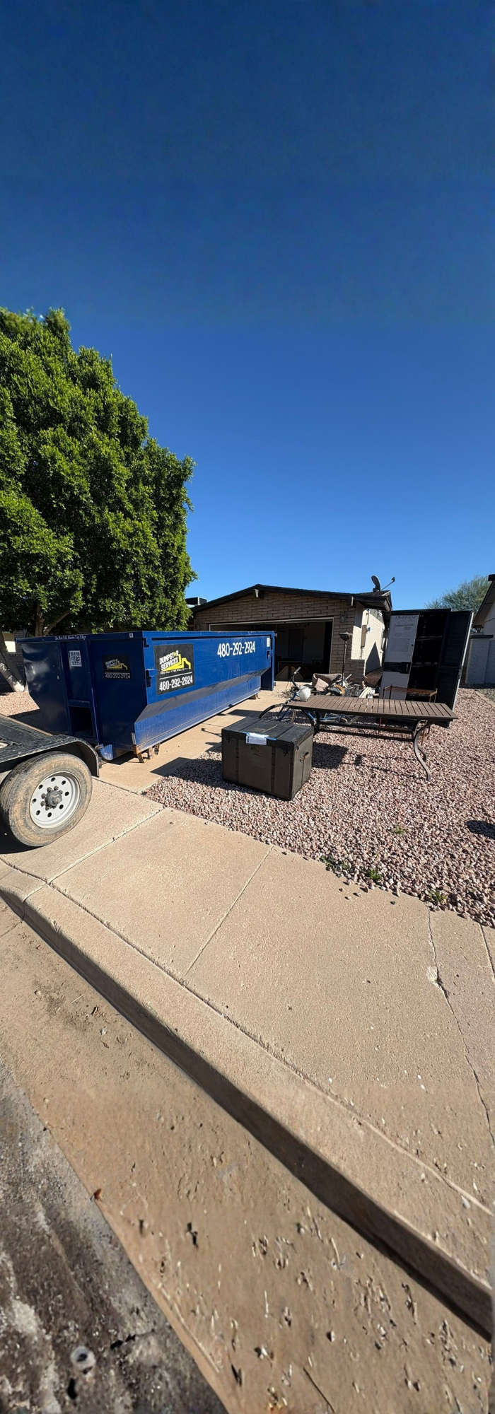 Dumpstar Services blue dumpster in front of a yellow Penske moving truck.