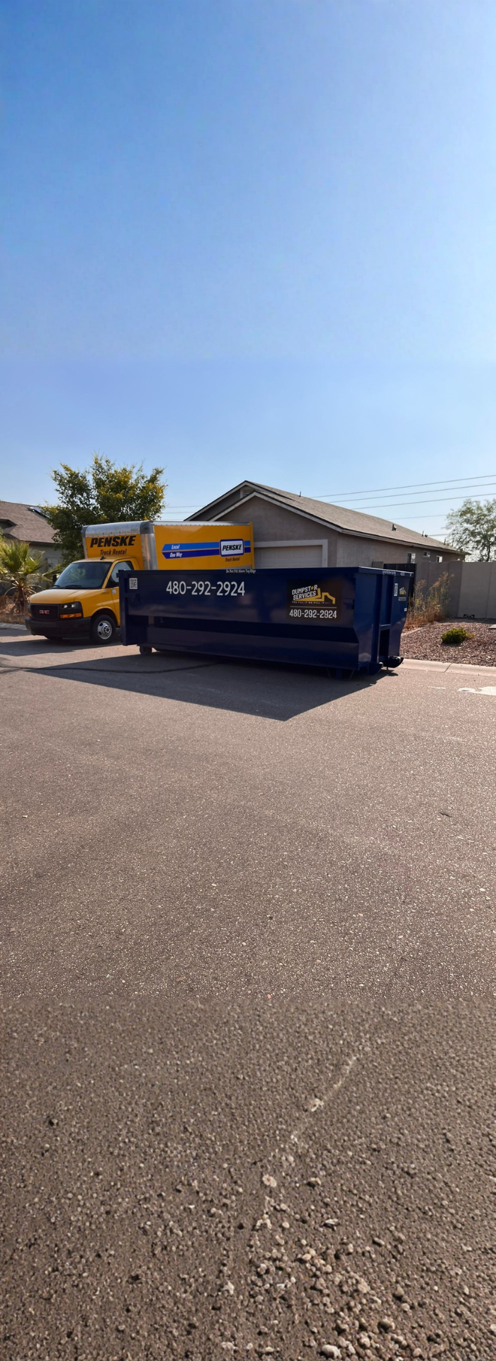  Dumpstar Services blue dumpster and a Penske truck on an asphalt road.