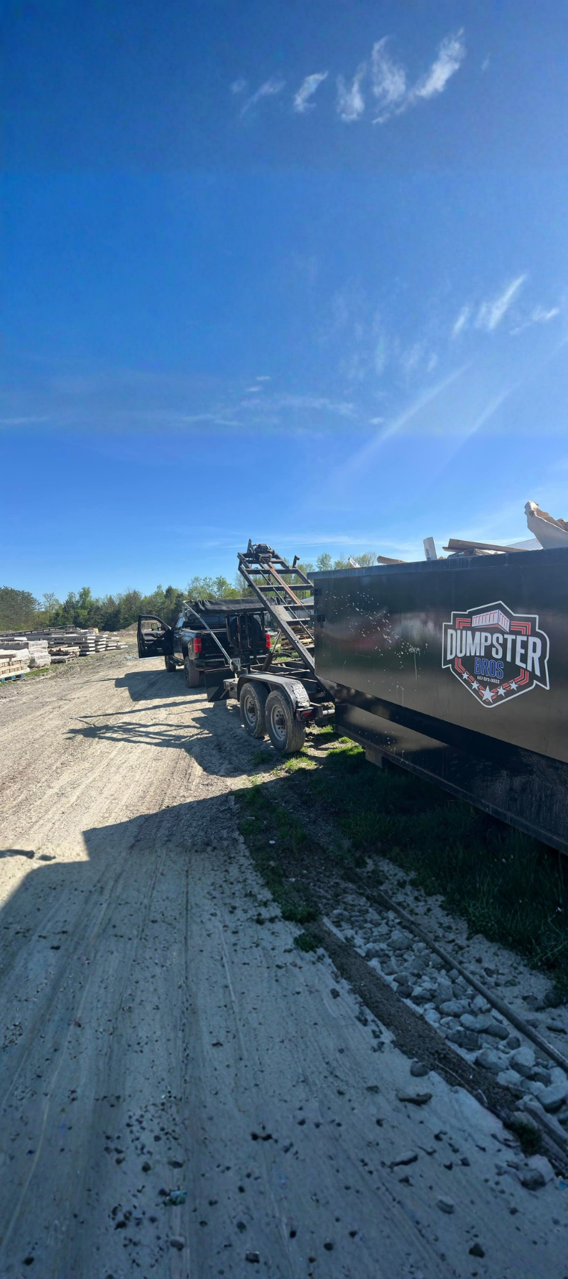 Dumpster Bros black roll-off dumpster being loaded onto a trailer.
