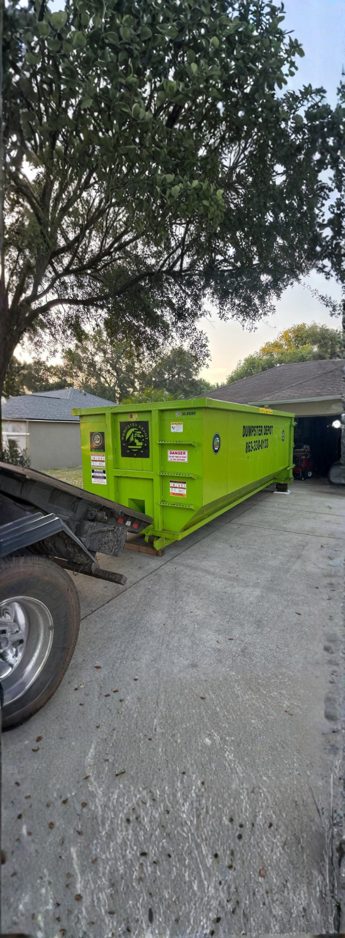Green Dumpster Depot roll-off container in a residential driveway. Green Dumpster Depot roll-off container in a residential driveway.