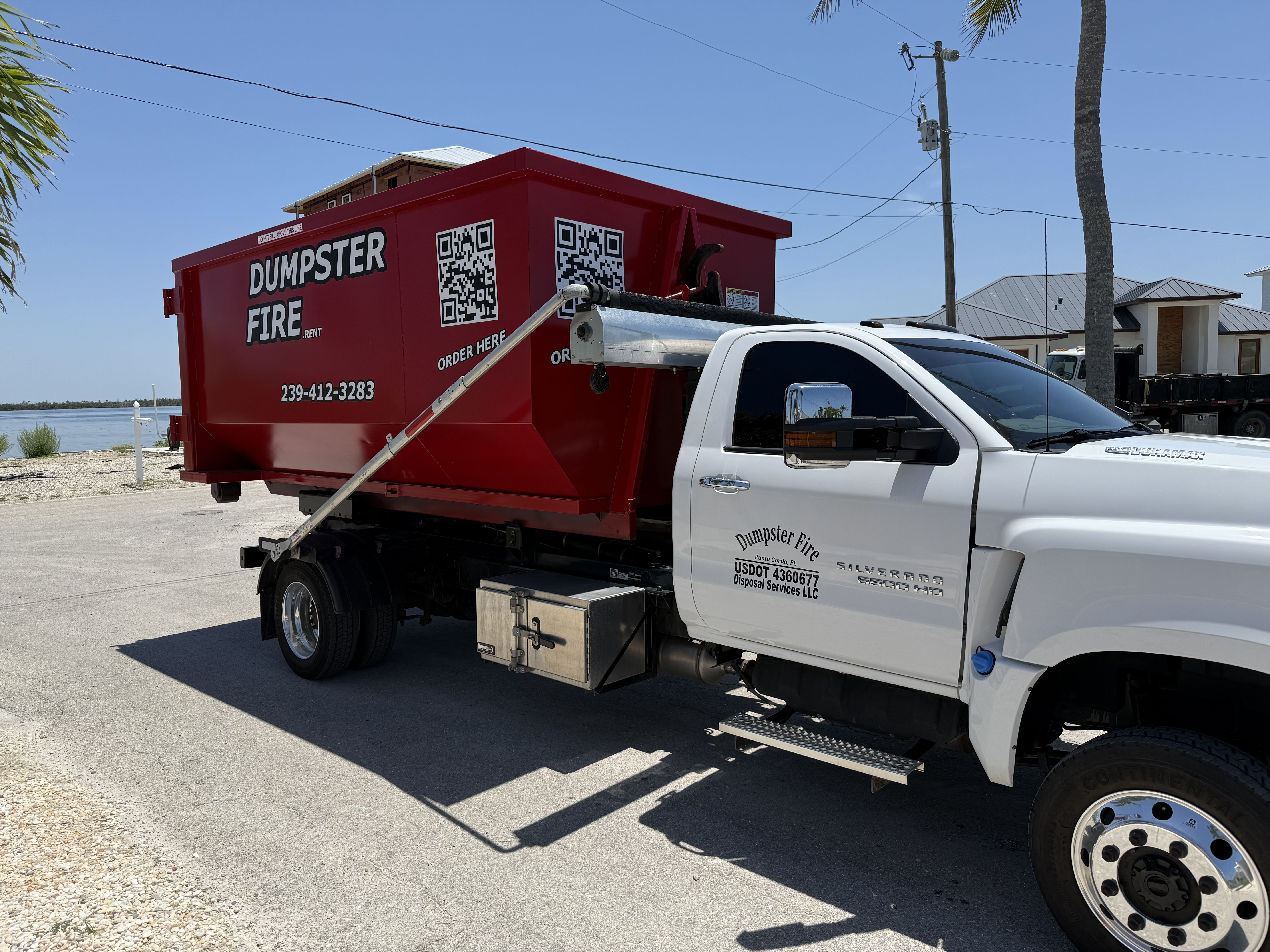 Dumpster Fire truck delivering red bin near waterfront Dumpster Fire truck delivering red bin near waterfront