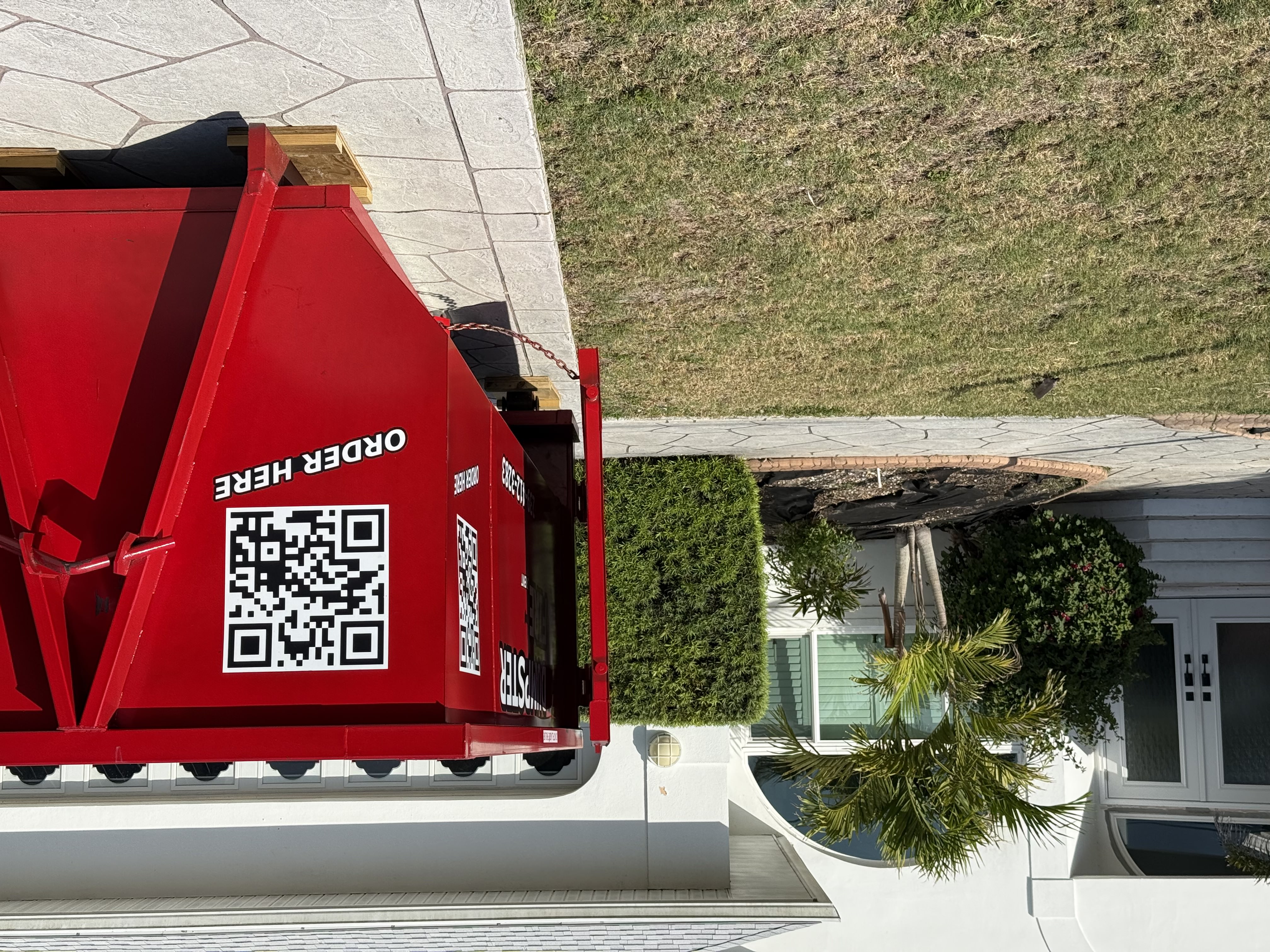 Red Dumpster Fire rental bin in driveway with QR code Red Dumpster Fire rental bin in driveway with QR code