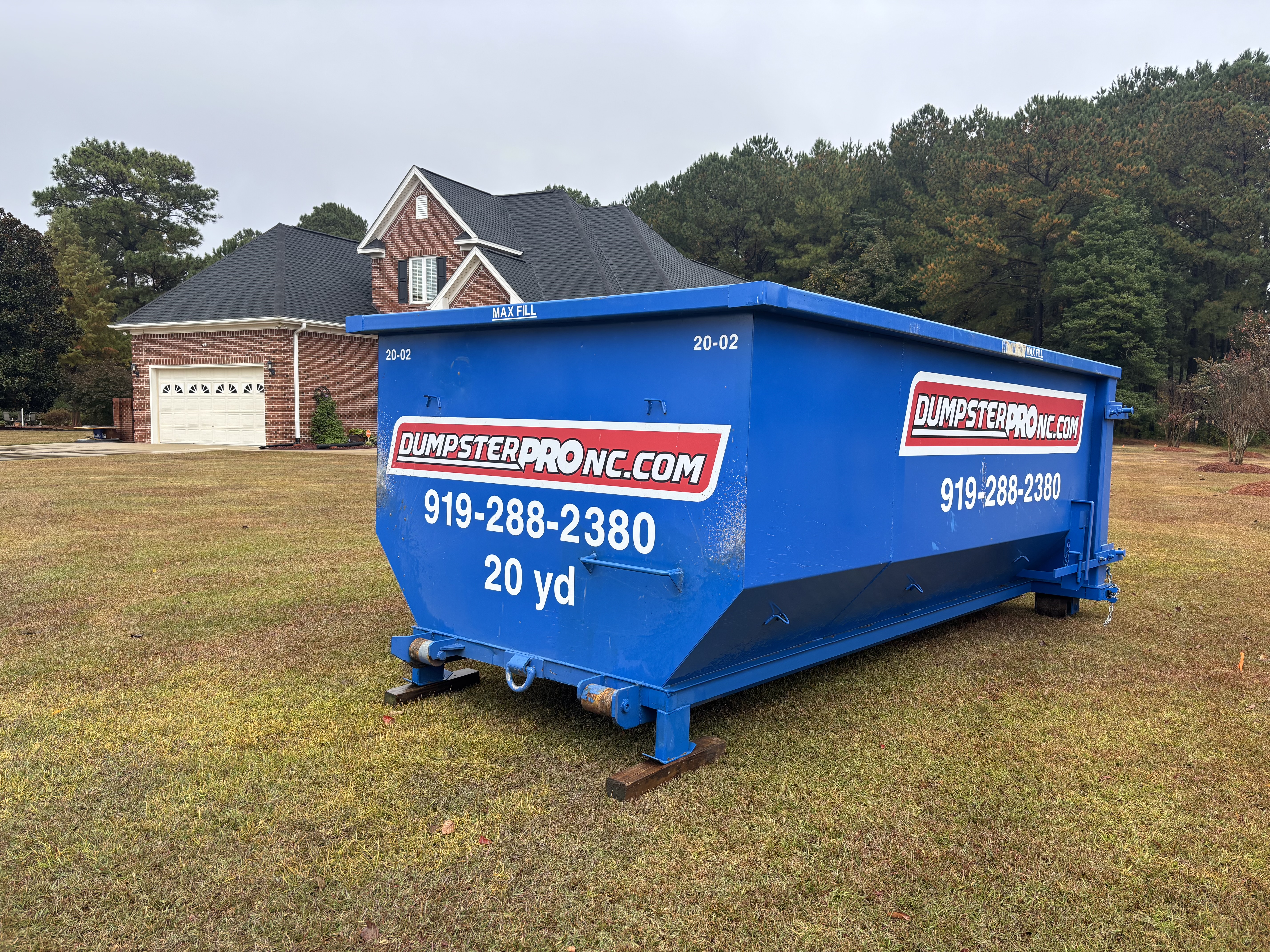 Blue dumpsters in front of a brick building by Dumpster Pro NC