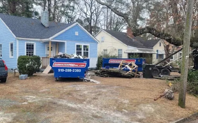 Blue roll-off dumpster placed in front of a residential home driveway by Dumpster Pro NC