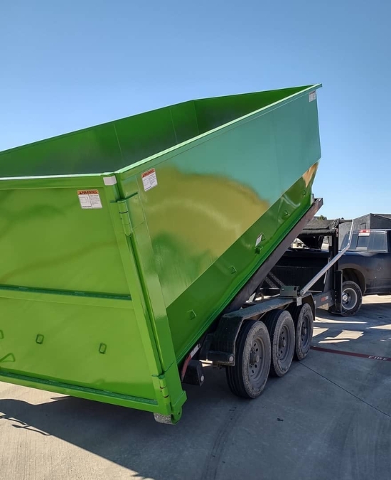Green roll-off dumpster loaded on a delivery trailer from Dumpster Supply