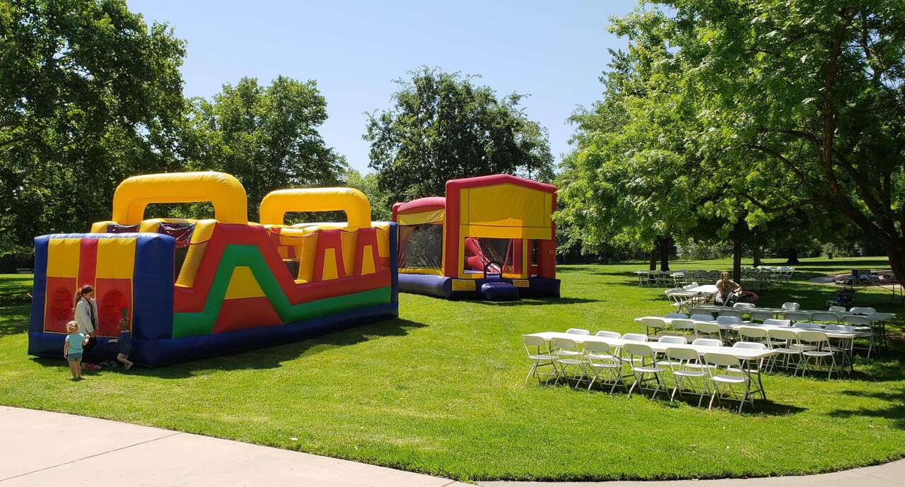 Bounce house obstacle course tables and chairs set up for a park party in Carmichael CA