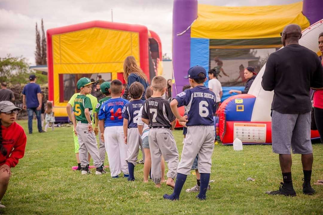 Little League players enjoying bounce houses and inflatable games at a youth baseball event