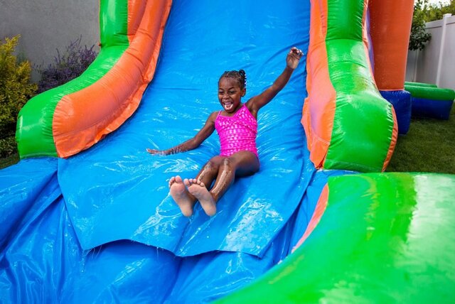 A girl at the top of an inflatable slide at a party